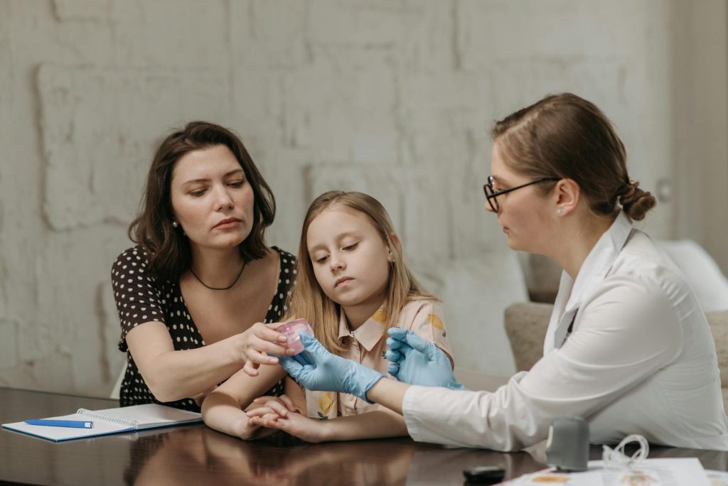 doctor and mother sitting with daughter by table